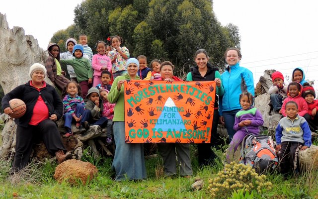 Die kleuters en personeel van Môresterretjies Pre-School by hulle Kilimanjaro-plakkaat, met regs van die plakkaat vlnr Sandra Wessels en Melinda du Plessis wat Kilimanjaro vir ‘n fondsinsamelingsprojek gaan uitklim